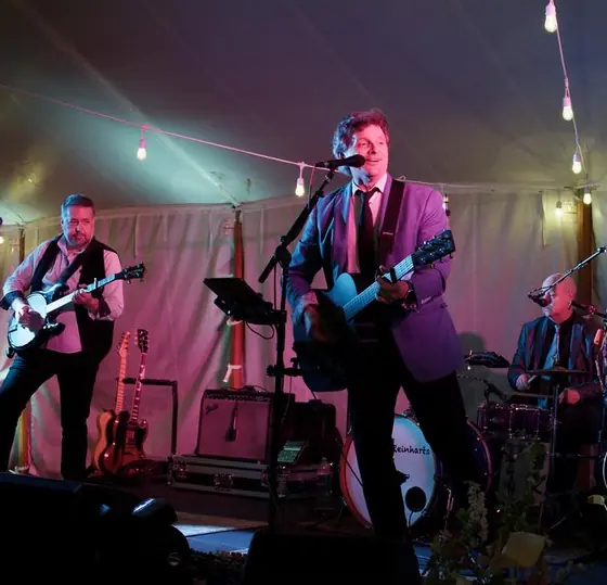 The Jangling Reinharts performing under a string-lit tent, the band's name on the bass drum