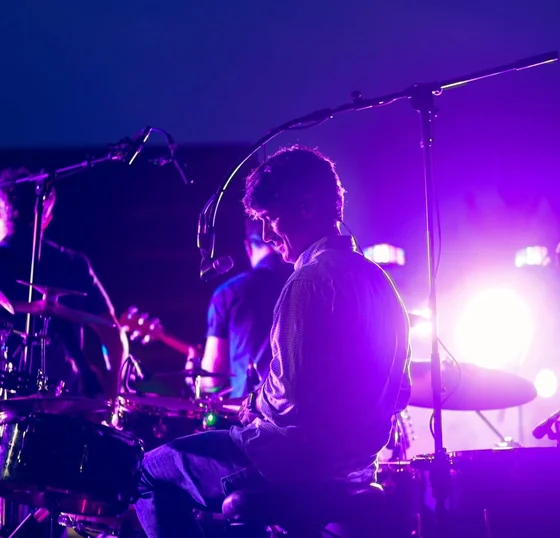 Winston Price of Acoustic Underground drumming under stage lights